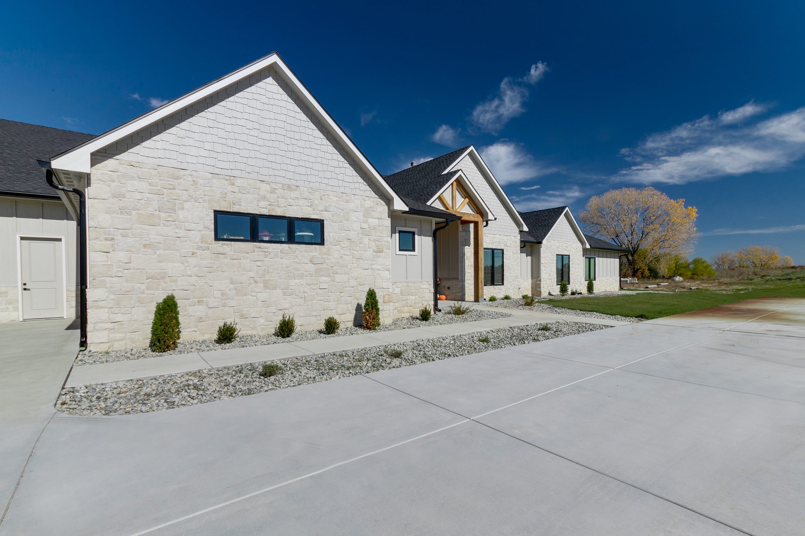 Row of modern stone houses with white siding and a bright blue sky above.